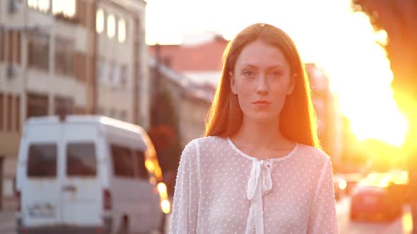 Urbanistic Portrait of Ginger Female Which is Walking in the City on Warmly Evening alt