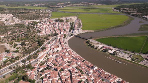 Birds eye view of riverside parish townscape and rice paddy fields alongside sado river channel. alt