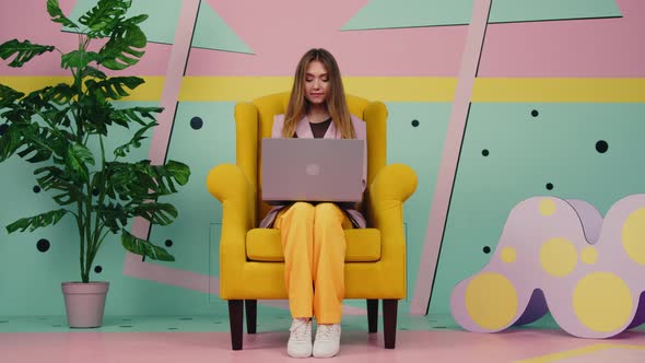 Woman In Yellow Armchair Is Using Laptop