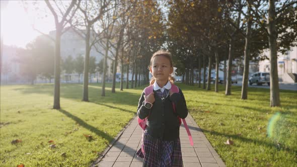 Young Girl in School Uniform is Walking in the Park at Sunny Weather Steadicam alt