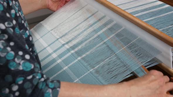 Woman puts on glasses and begins to handweave