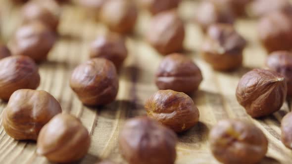Sliding Shot of Dried Hazelnuts Lying on a Textured Wooden Table Surface alt