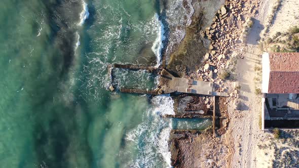 Eroded building at Trenc Beach in Mallorca Spain with concrete foundation pounded by waves, Aerial t alt