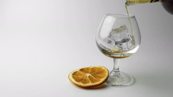 a Glass of Whiskey with Ice and a Slice of Orange on a White Background alt