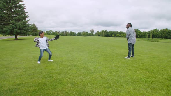 Positive African American Father and Son Training Baseball in Park alt