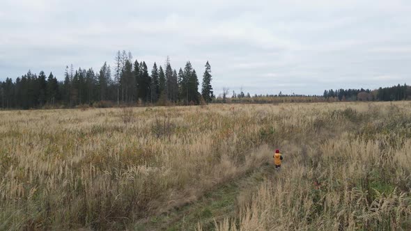 Boy Child in a Yellow Vest and Red Hat Runs alt