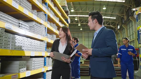 Asian business woman work in industry manufacturing plant with partner. alt