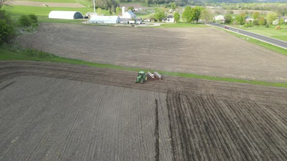 View of farmer prepping field for planting with neat straight rows in the dirt.