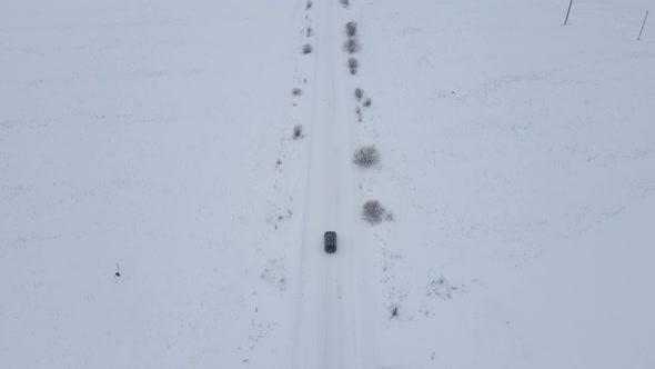 Aerial View Car Drives Through Slippery Snow Covered Road