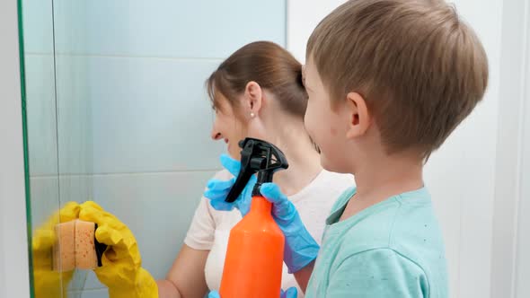 Little Toddler Boy Applying Chemical Detergent From Spray While Mother Rubbing and Cleaning Bathroom alt