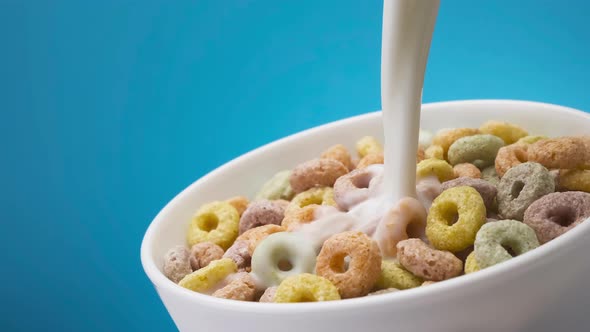 Milk pouring into bowl of colorful corn rings alt