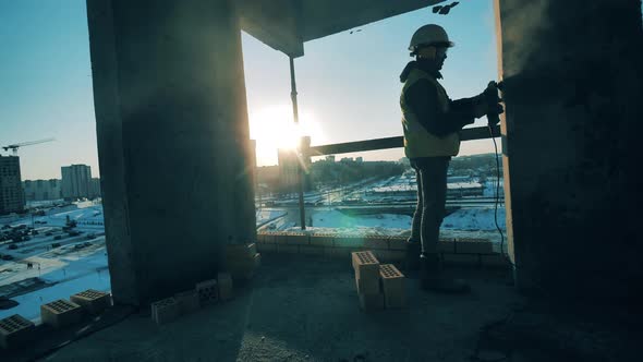 Male Worker Is Buffing a Wall of a Multistory Building in Progress. Construction Worker at a alt