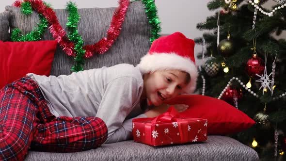 Preteen Boy Wakes Up and Rejoices at a Christmas Gift at Home alt