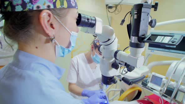 Dentist looking through a microscope alt