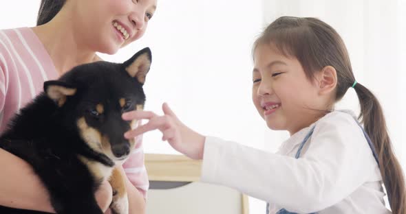 Mother and daughter playing with black dog on bed (1)