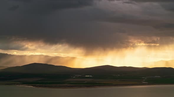 Sun rays beaming light through rainstorm moving over the farmland by Utah Lake alt