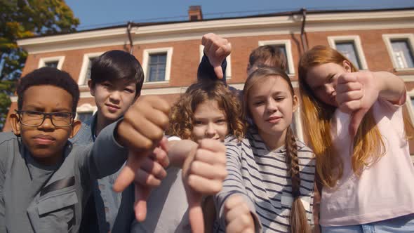 Group of Diverse Children Showing Dislike with Thumbs Down Standing Outdoors alt