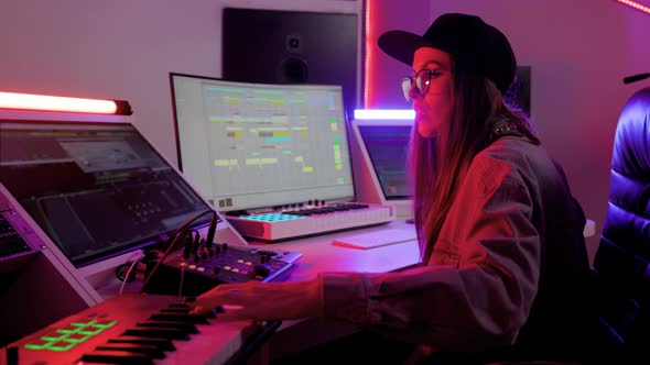 Woman in Designer Glasses Cap and Headphones Working in the Recording Studio with Computer and Mixer alt