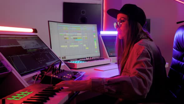 Woman in Designer Glasses Cap and Headphones Working in the Recording Studio with Computer and Mixer