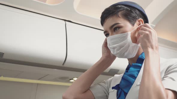 Female air hostess wearing protective mask before service passenger on airplane