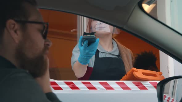Bearded Man Driver in Car Paying with Credit Card for Fast Food Order at Drive Thru Counter alt