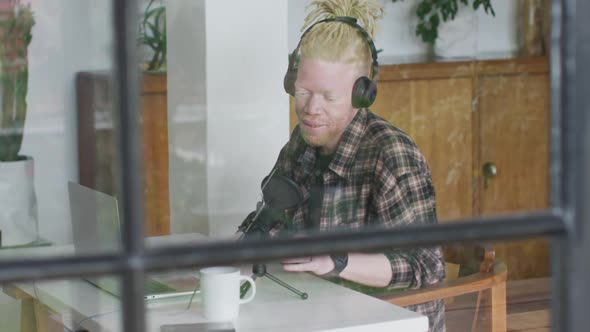 Happy albino african american man with dreadlocks making podcast alt