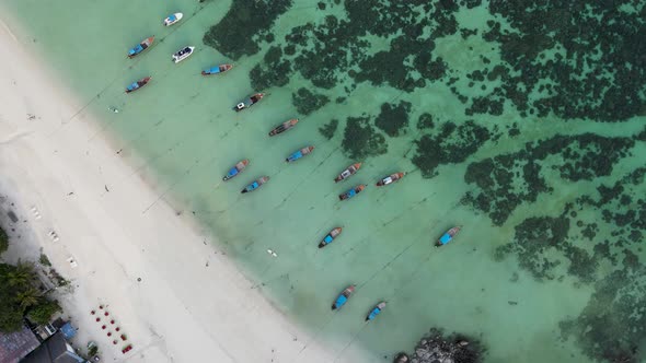 top down view of longtail boats docked on white sand beach in Koh Lipe Thailand, aerial, zoom out, c alt