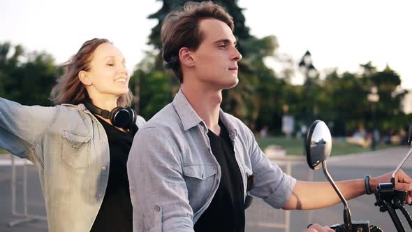 Young Couple Enjoying Riding on Electric Minibike Through Park in Summer alt