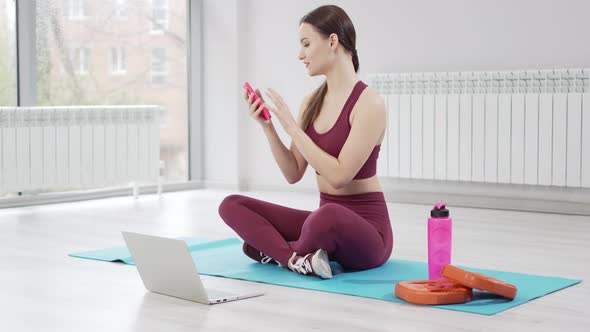 a Young Woman with Laptop Sends a Message to Students for an Online Workout alt