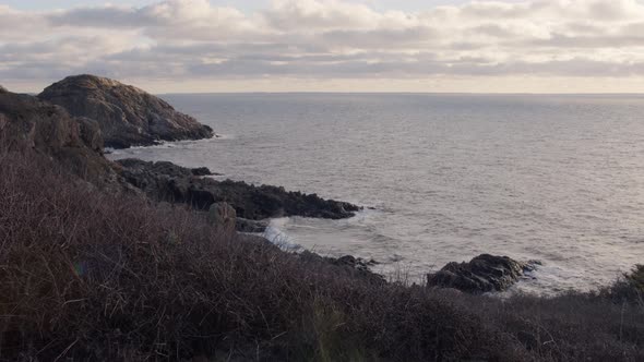 Ocean cliff at sunset with cloudy sky and eternal horizon. Static shot in slow motion. alt