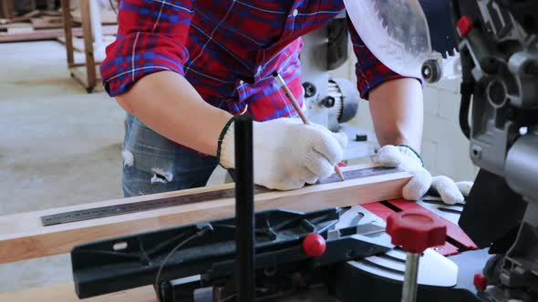 Smart architect mark the pencil line on wood before cutting by electronic saw in workshop alt