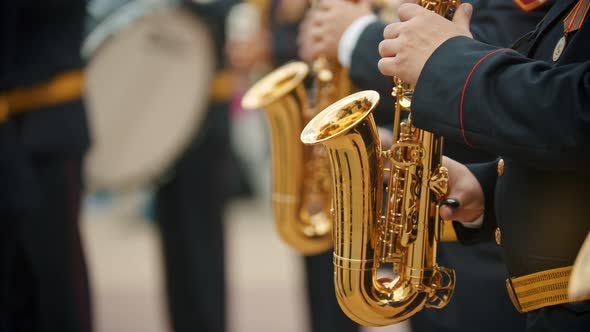 A Wind Instrument Parade - Men in Dark Costumes Playing Saxophone Outdoors - Military Music Festival alt