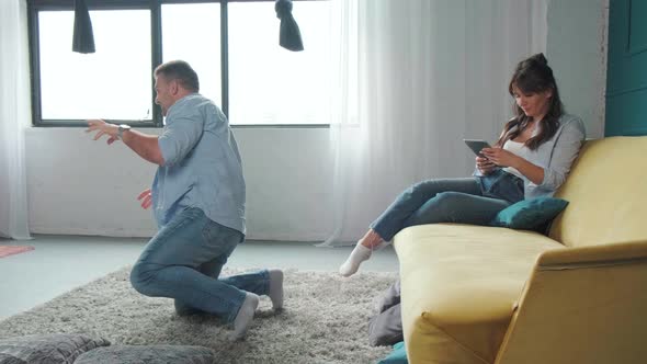 Little Girl is Playing with Her Father While Her Mother Works Using a Tablet alt