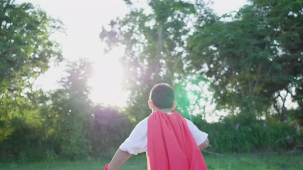 Back view of Asian boy holding sword and running in the park alt