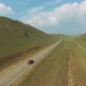 Aerial view above bus and car driving along empty countryside road between hills on sunny day - VideoHive Item for Sale