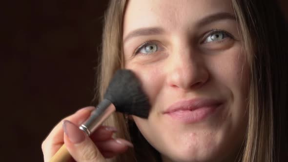 Face of a Beautiful Young Woman Applying Blush with a Brush on Her Face alt