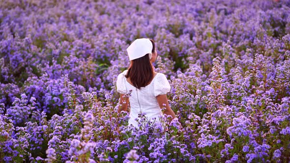 Young woman traveler relaxing and enjoying with blooming flower field in the morning