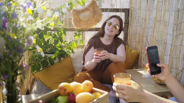 Woman with Drink Sings While Friend Shoots Video on Terrace