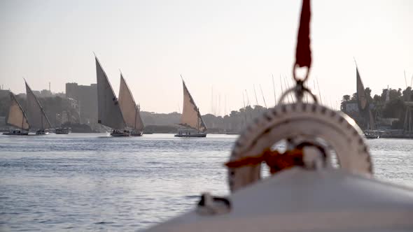 View of the front of a felucca with feluccas sailing in the backgroudn during golden hour on the Nil alt
