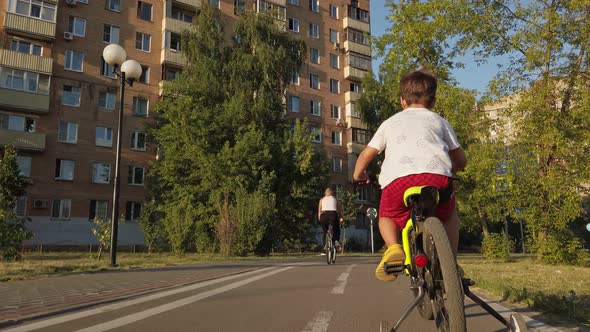 a Little Boy Famously Rides a Children's Bike on a Bicycle Path in the Summer alt