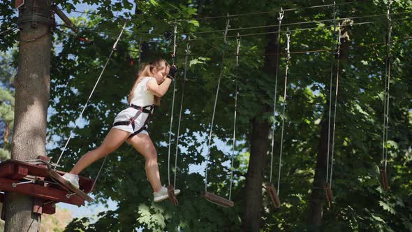 Young Teen Brunette Overcomes Obstacles in the Rope Town