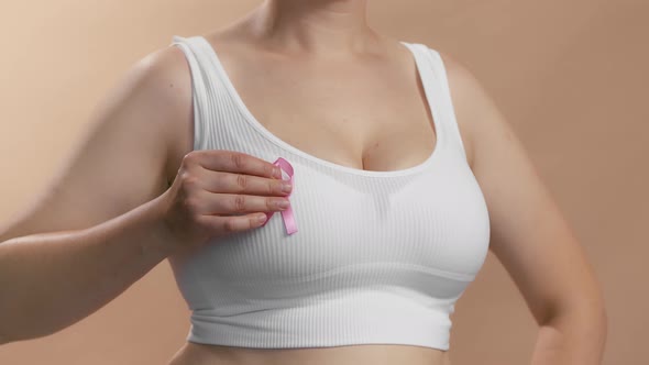 Young Caucasian Female in a White Seamless Bra Put Pink Ribbon for Breast Cancer