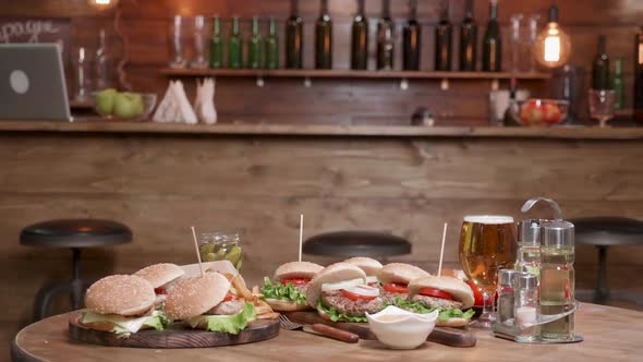 Very Big Selection of Burgers on Wooden Table in Front of a Bar alt