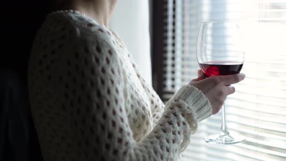 the camera moves around a glass with red wine in the girl s hand alt