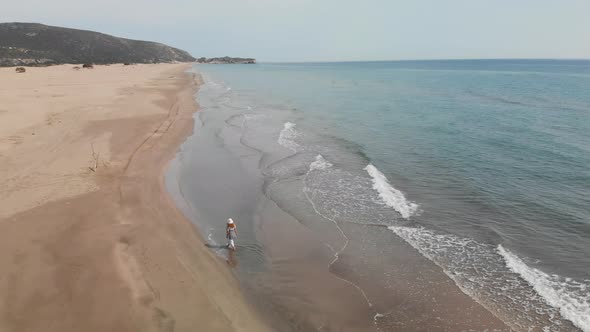 Aerial Drone Top Down View of Woman Walking Alone the Beach alt