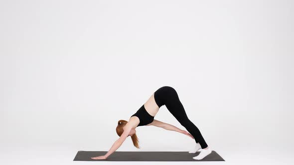 Sporty Young Female Training In Studio Making Downward Facing Dog Exercise