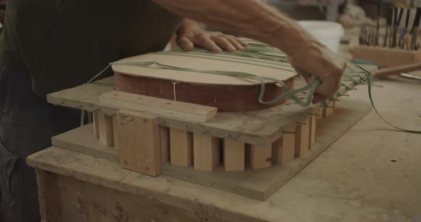 luthier starching rubber bands over guitar mold