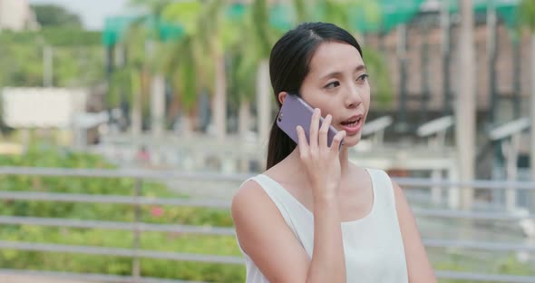 Woman talk to cellphone in city alt