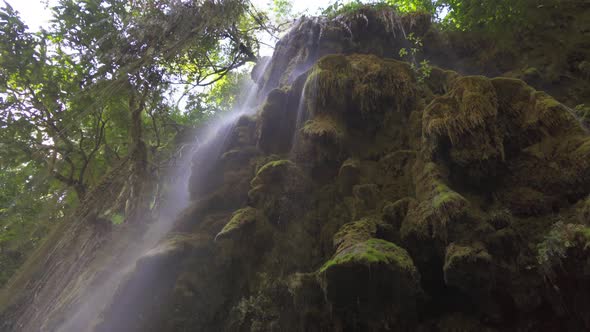 Waterfall with natural stalactite and stalagmite rock stone cliff hang from cave ceiling in cave. alt