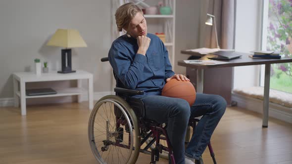 Live Camera Zoom in Desperate Caucasian Disabled Man in Wheelchair with Basketball Ball alt